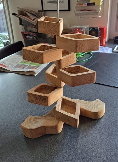 Bakjes VERKOCHT Houten sculptuur met een draaiende structuur en open bakjes.