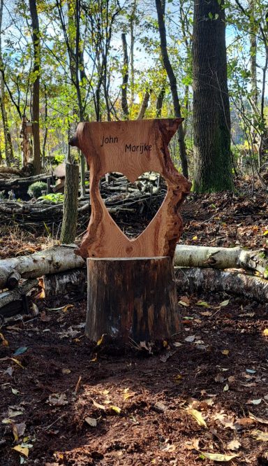 Gedenkbeeld VERKOCHT Een houten sculptuur in het bos met een hartvormige uitsnijding.