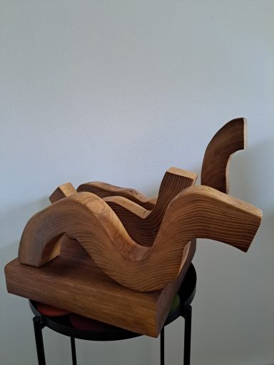 Wave Abstract houten sculptuur met vloeiende, golvende vormen op een zwarte standaard.