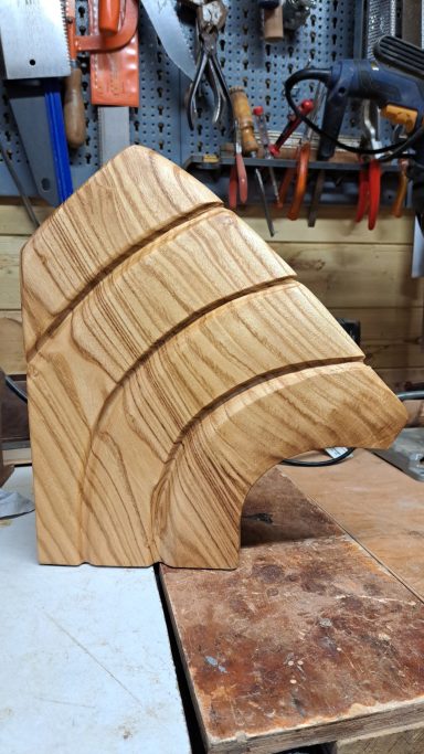 Maanhout 80 Euro VERKOCHT Houten sculptuur met gebogen lijnen en verschillende lagen in een werkplaats.
