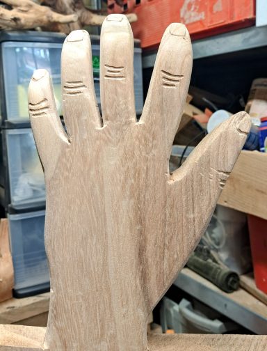 Hand VERKOCHT Houten hand met vingermarkeringen, staand in een werkplaatsomgeving.