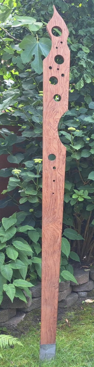 Idee! 175 Euro Houten staak met uitgesneden patronen, geplaatst tussen groene planten.